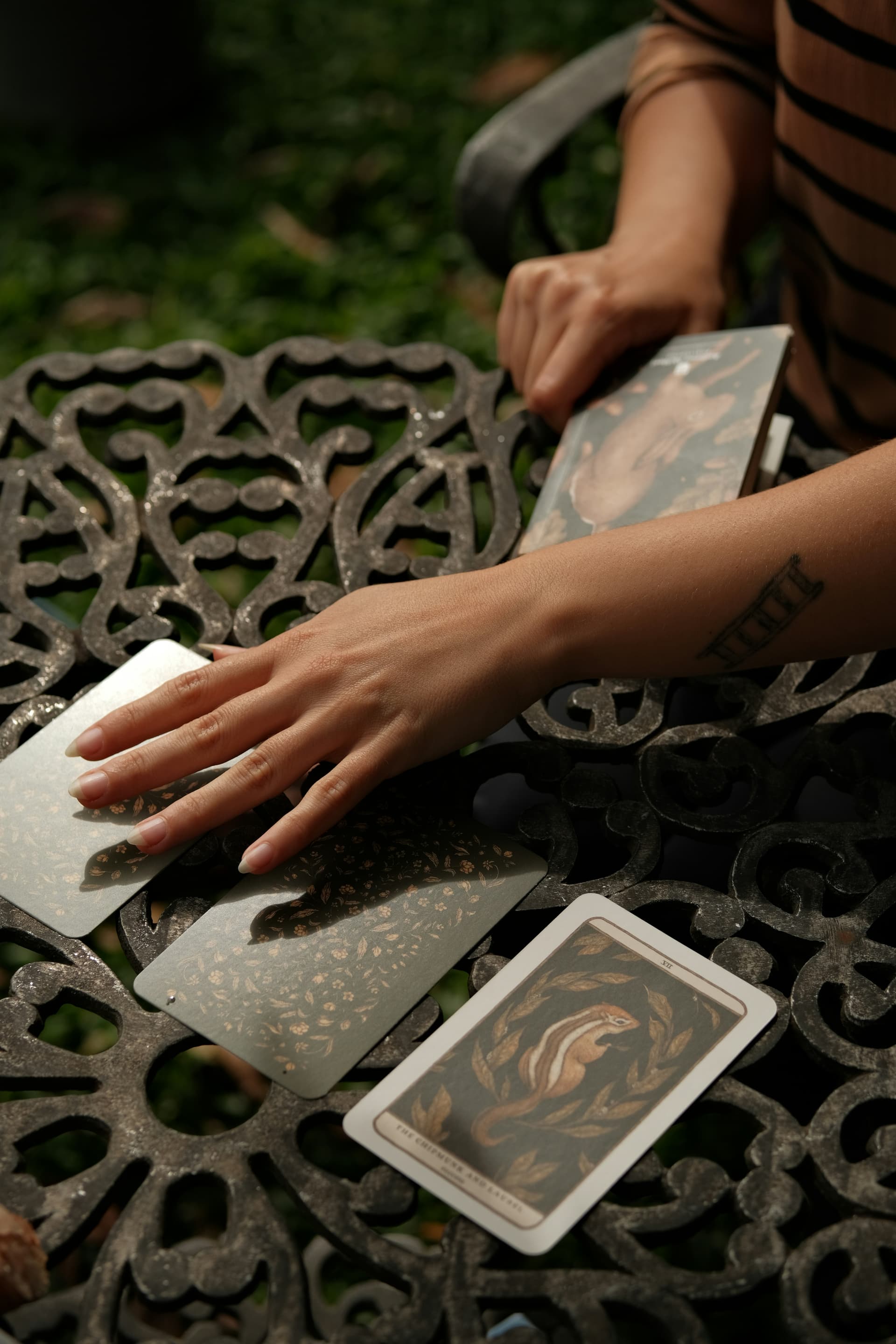 Händer som lägger ut tarotkort på ett bord utomhus